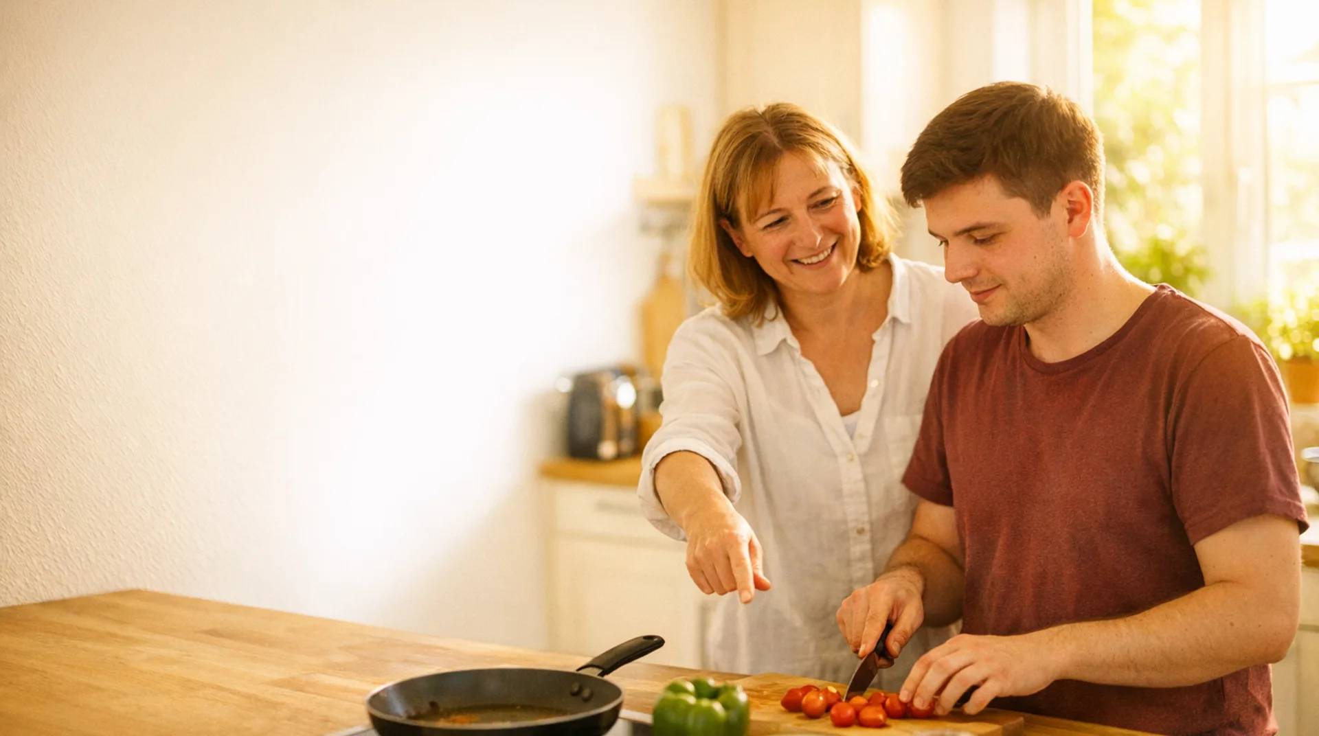 Ergotherapeutin übt mit einem jungen Mann in der Küche Schritt für Schritt das Kochen